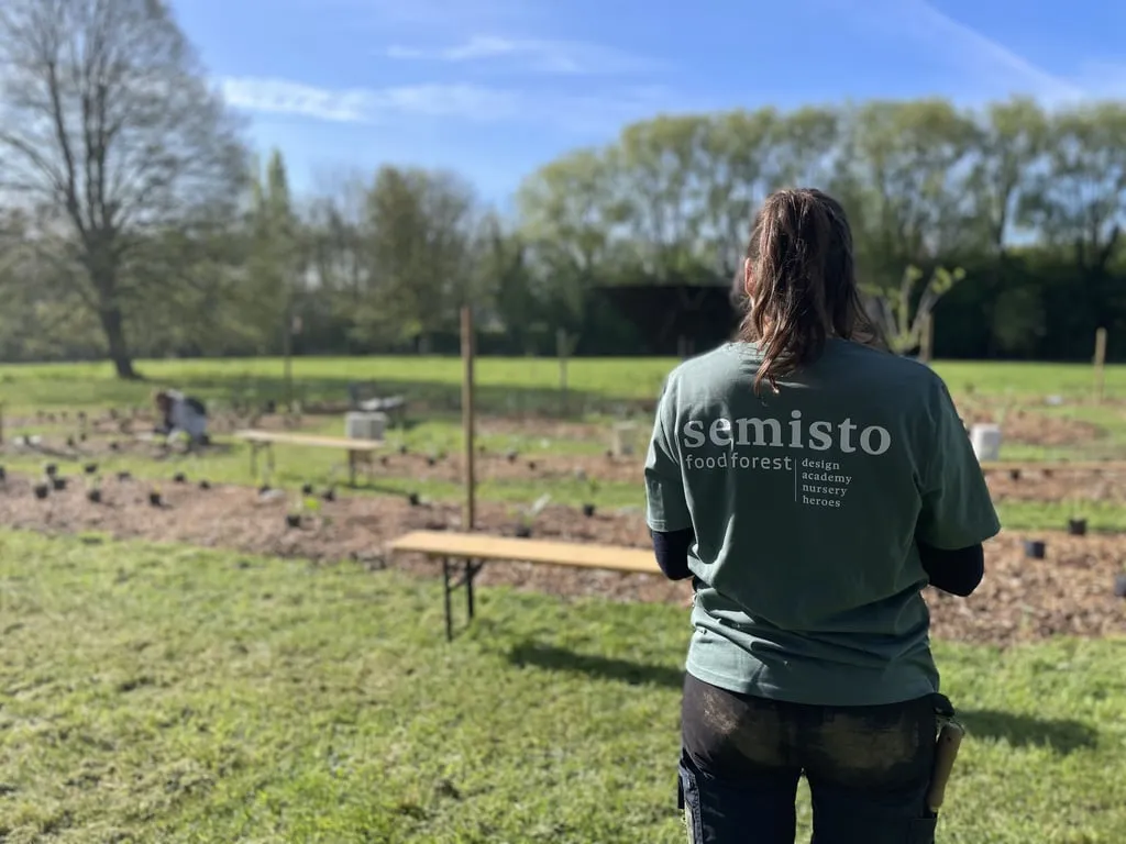 Membre de Semisto observant un site de jeune forêt comestible en cours de plantation