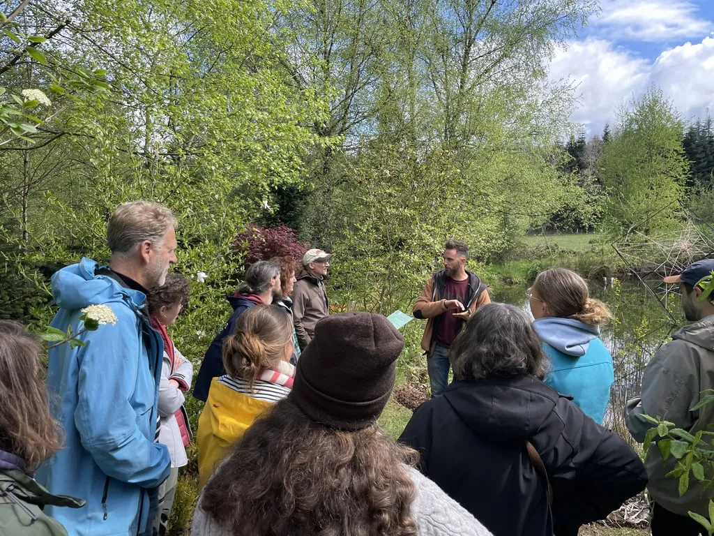Visite guidée du jardin-forêt : groupe rassemblé près d’une mare au printemps