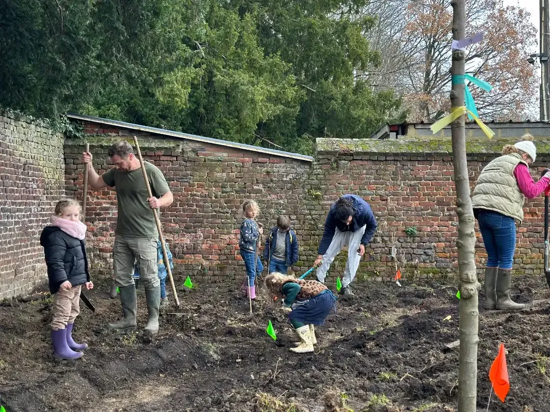 Plantation participative le long d'un mur de brique avec des enfants