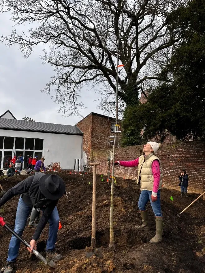 Personnes plantant de jeunes arbres devant un bâtiment
