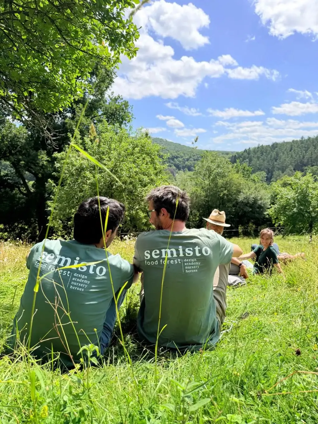 Membres de l'équipe Semisto en t-shirts assis dans une prairie