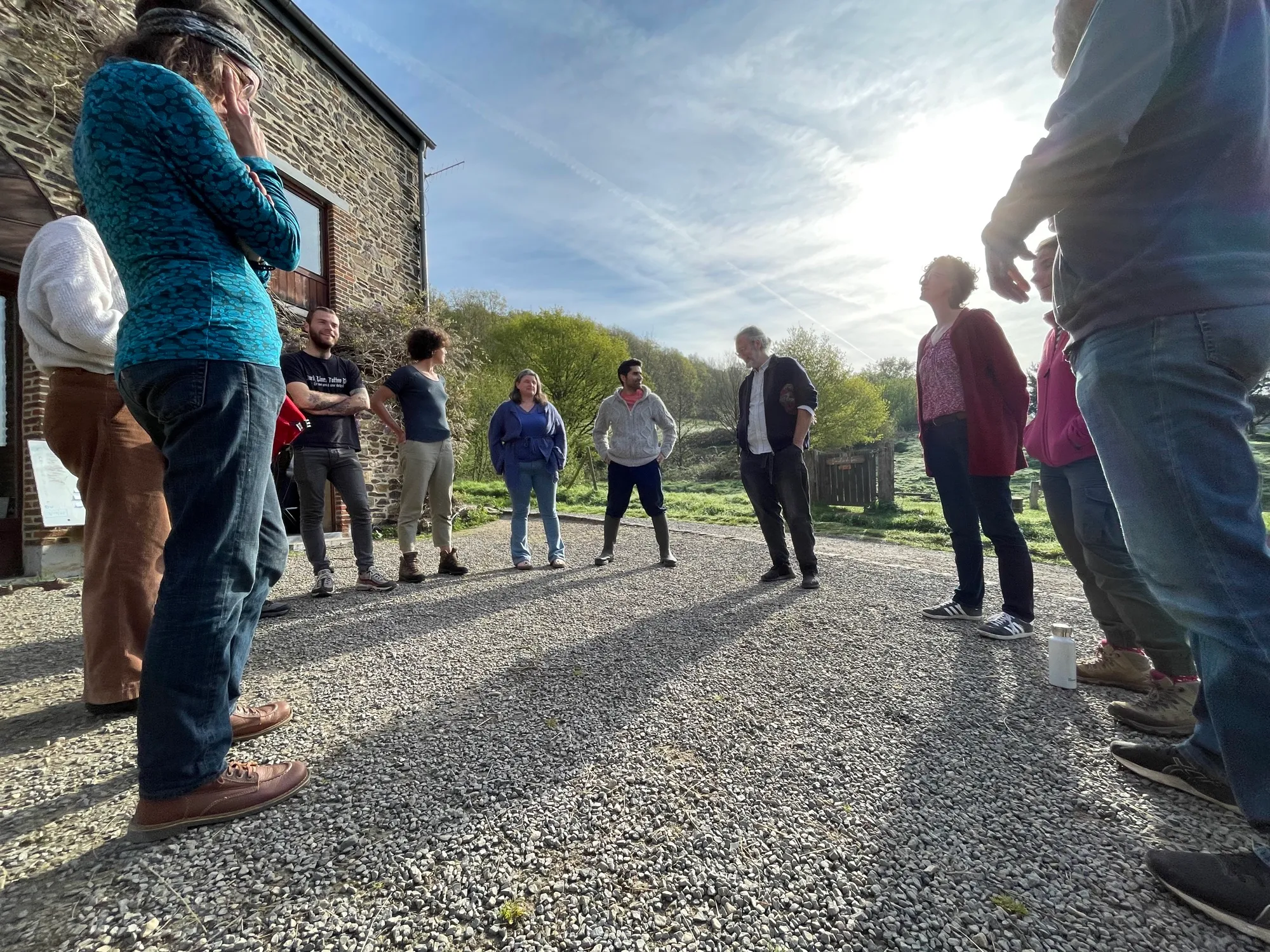 Le collectif réuni en cercle devant la grange, dans la lumière du matin